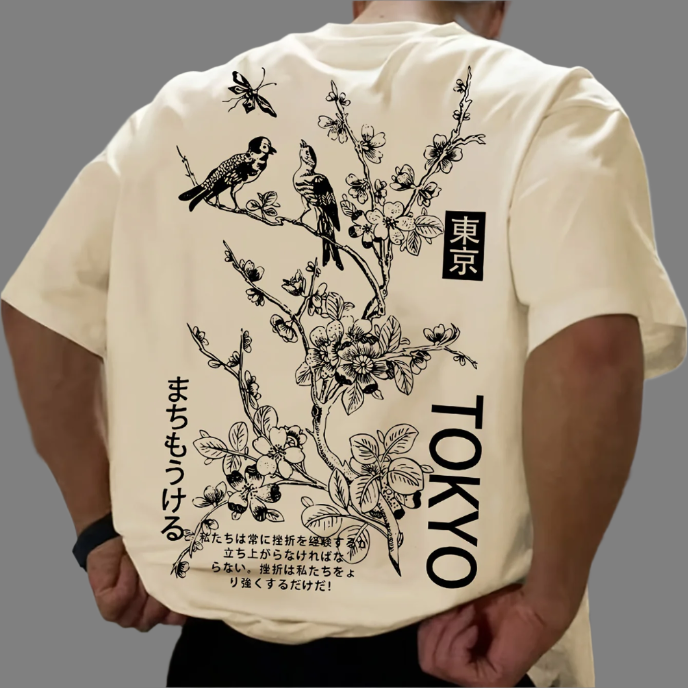 Light-colored oversize t-shirt with a graphic of birds on a flowering branch, "Tokyo" text in English and Japanese, and additional Japanese text on the back.