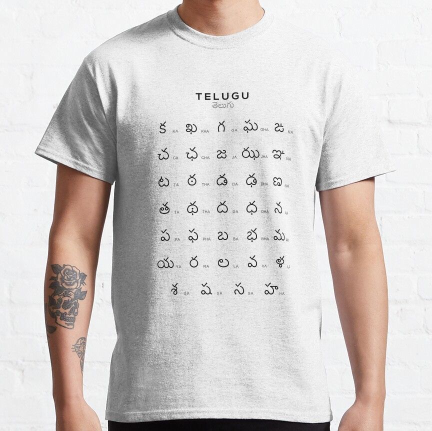 Light gray t-shirt with the English word 'TELUGU' and the Telugu word 'తెలుగు' (Telugu) above a grid displaying the full Telugu alphabet. Educational design for language learners on a comfortable t-shirt.