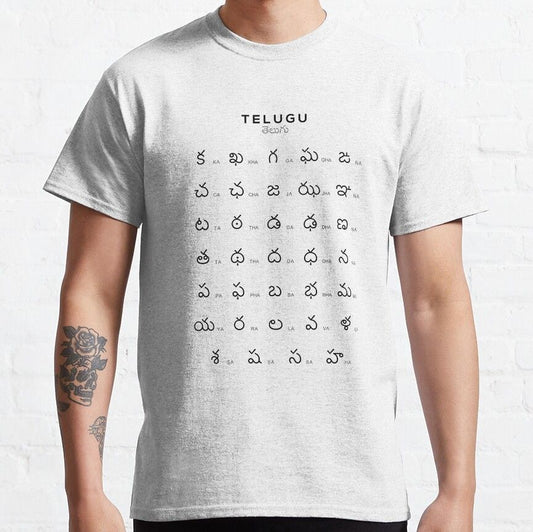 Light gray t-shirt with the English word 'TELUGU' and the Telugu word 'తెలుగు' (Telugu) above a grid displaying the full Telugu alphabet. Educational design for language learners on a comfortable t-shirt.