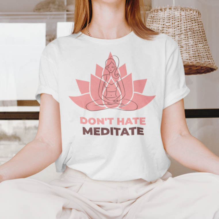 White t-shirt with "Don't Hate Meditate" text and lotus pose graphic, worn by a woman meditating.