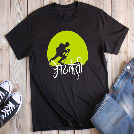 Black t-shirt with a lime green circle featuring a white hiker silhouette and the Marathi word "भटकंती" (hiking), styled with jeans and sneakers.
