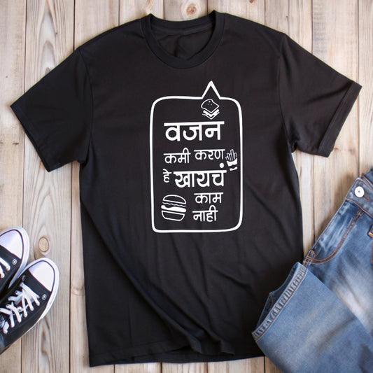  Black t-shirt with a speech bubble, burger, book, and white Marathi text "वजन कमी करणे हे खायचं काम नाही" (Losing weight is not a task for eating).