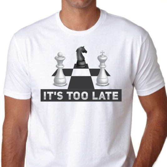 White t-shirt featuring a chess design with a black knight, two white pieces, and the text "IT'S TOO LATE" in bold.