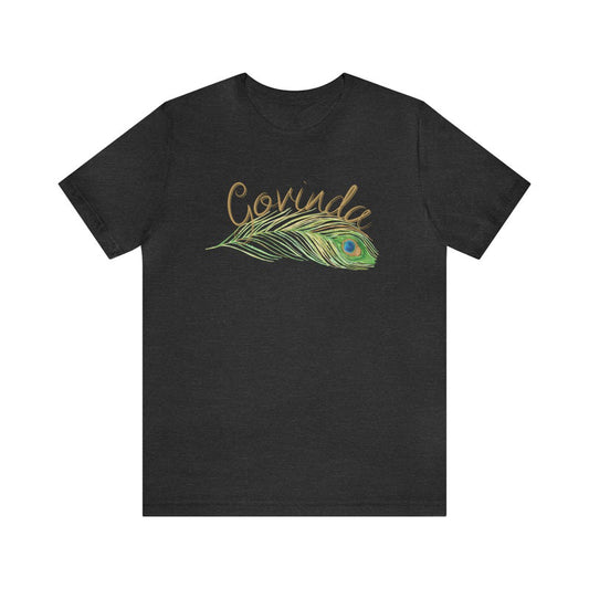 Dark grey jersey tee with "Govinda" in golden script above a detailed peacock feather illustration.