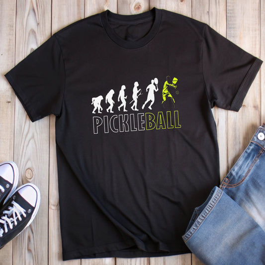 Black t-shirt with "Pickleball" text and evolution graphic ending in a pickleball player.