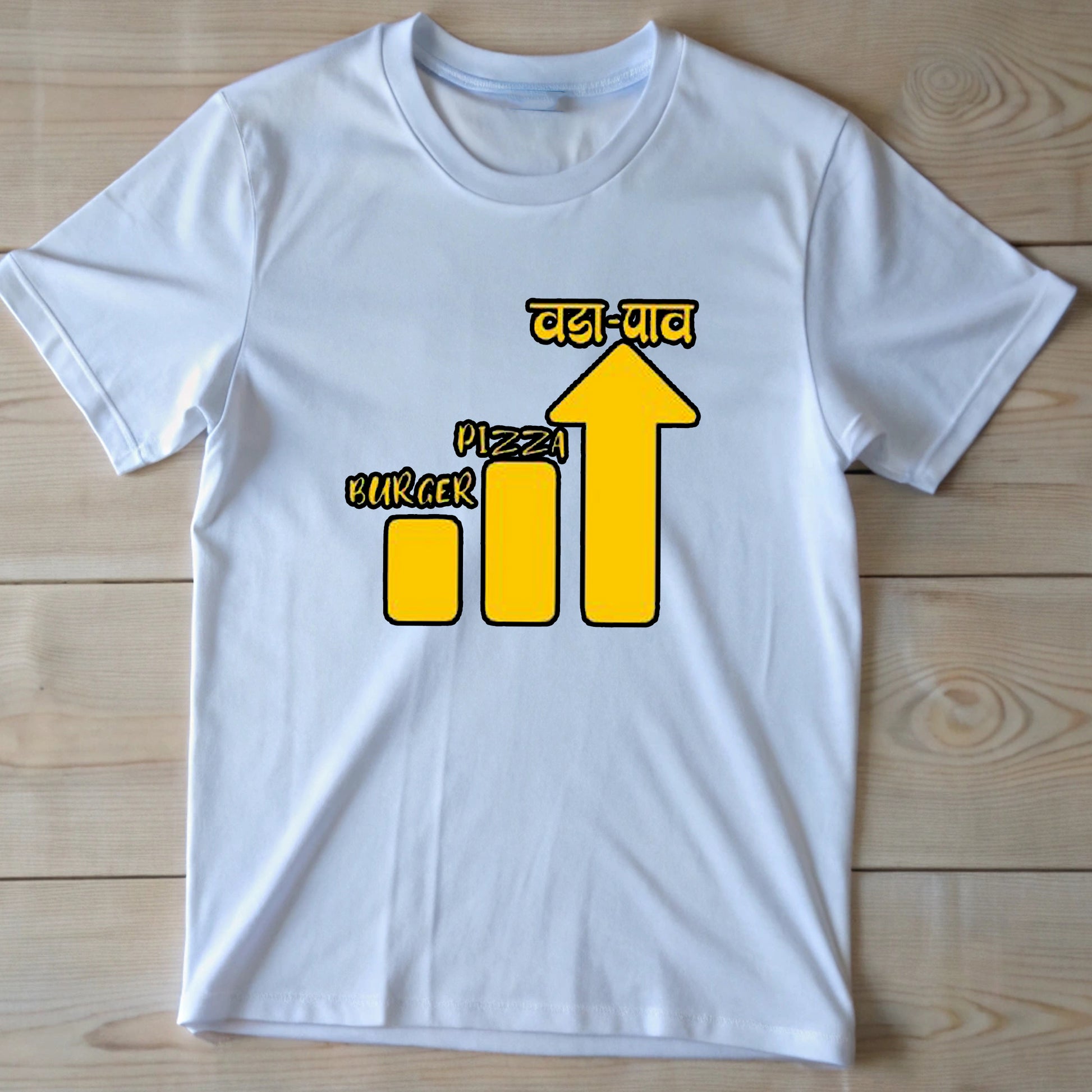  White t-shirt with a yellow bar chart showing "Burger" and "Pizza" lower than an arrow pointing up to "वडा-पाव" (Vada Pav).