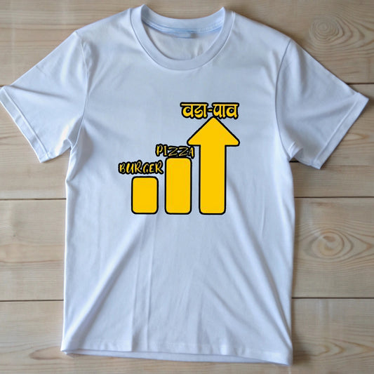  White t-shirt with a yellow bar chart showing "Burger" and "Pizza" lower than an arrow pointing up to "वडा-पाव" (Vada Pav).