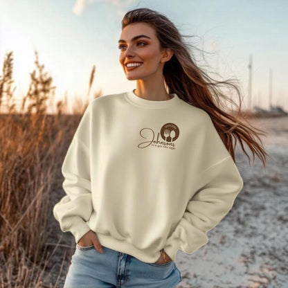 woman stand close cream sweatshirts with a small logo on the chest.